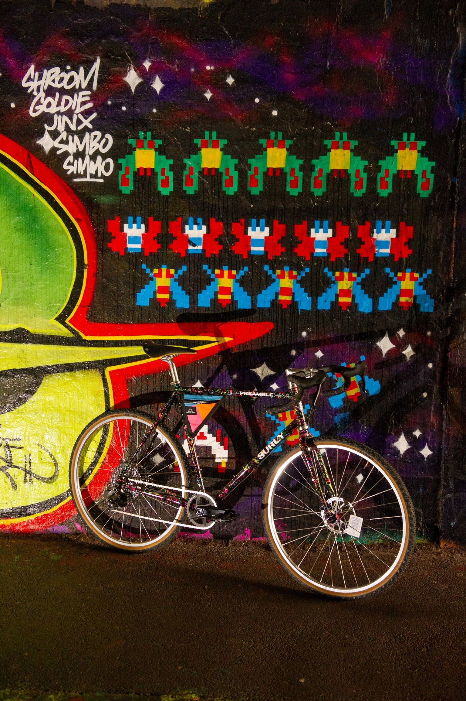 Custom painted Surly Preamble bike leaning against mural of space invaders